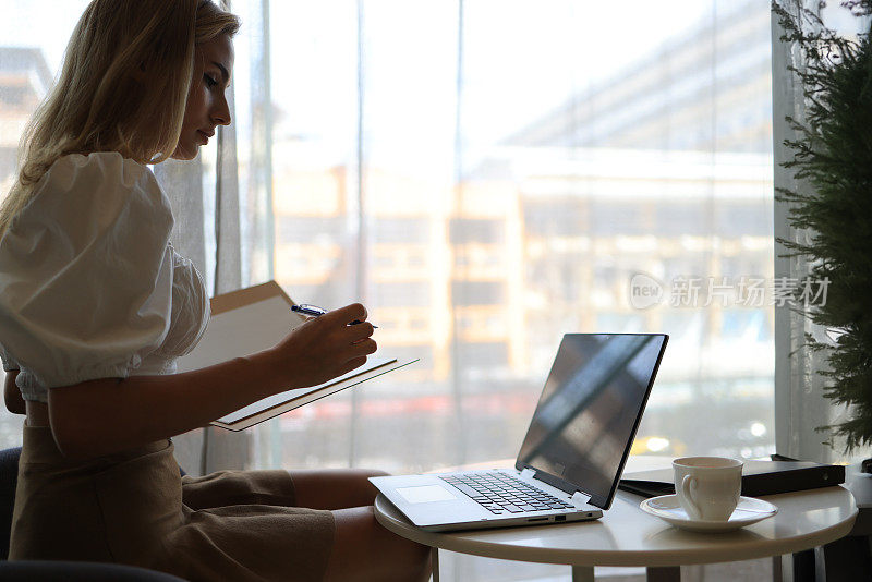 自信的女商人在舒适的室内共用办公空间里用笔记本电脑工作。远程工作概念