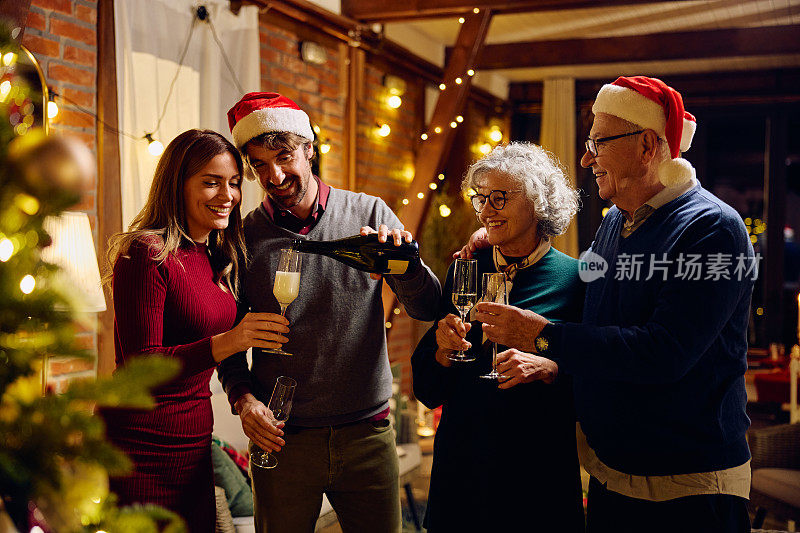 幸福的夫妇和他们的长辈一起喝香槟庆祝圣诞节。