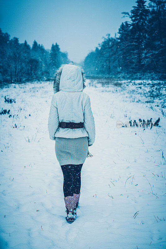 幸福的女人在冬天森林附近的白雪皑皑的草地