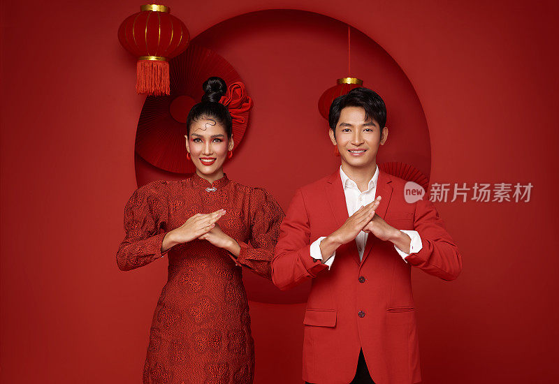 幸福的亚洲夫妇穿着红色休闲服装，用传统的红色背景装饰，祝贺2024年中国新年快乐。
