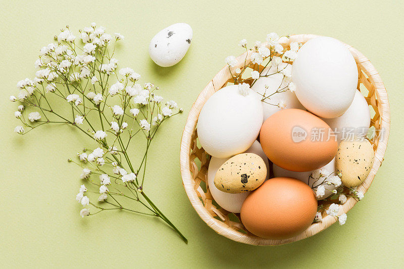 复活节作文快乐。复活节彩蛋在篮子里，在彩色的桌子上有吉思菲。自然染色彩色鸡蛋背景顶视图与复制空间
