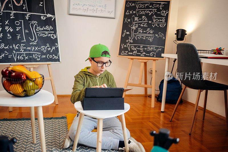 十几岁的男孩在家里用带键盘的数码平板电脑努力学习