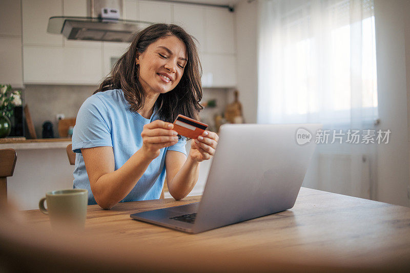 女人用信用卡在家里用笔记本电脑网购。