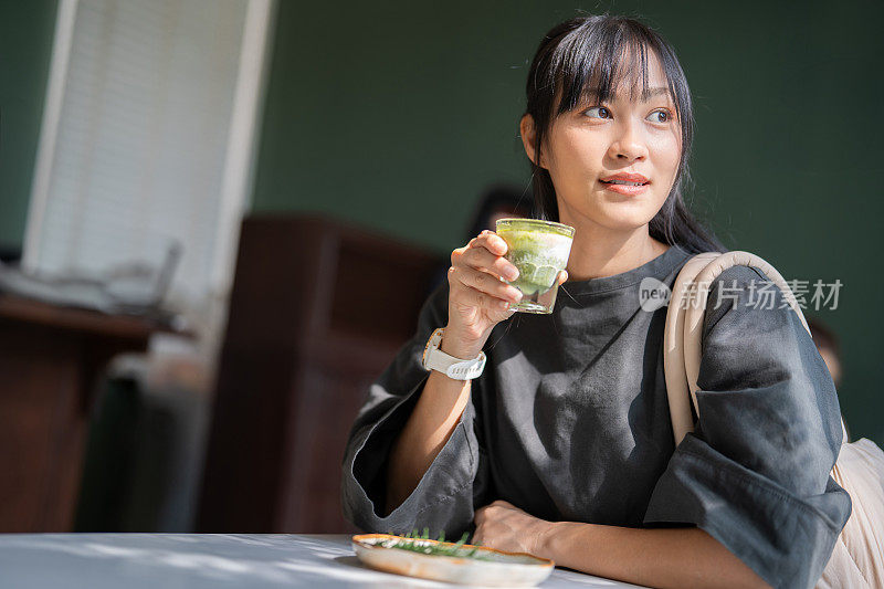 亚洲女人的热抹茶绿茶在现代咖啡馆激发了好主意。