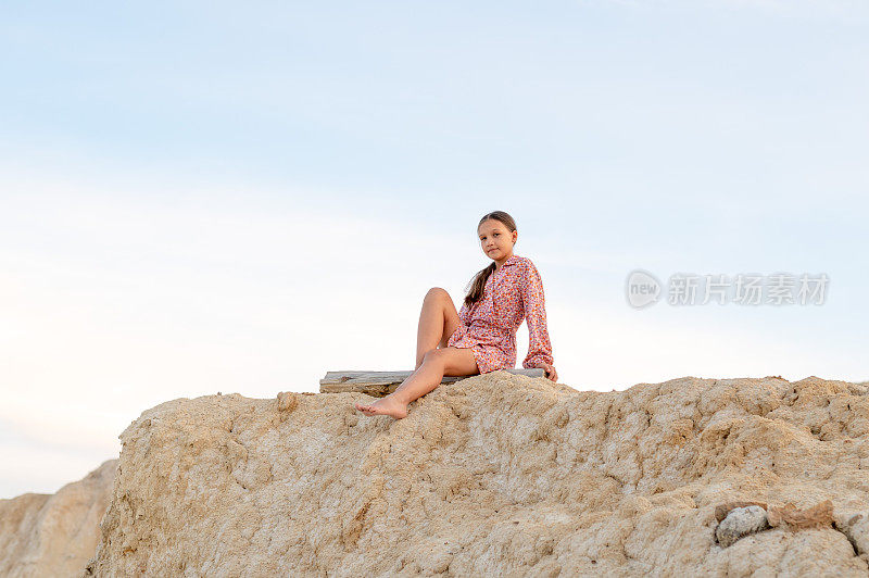 十几岁的女孩在大自然中休息，一个女孩坐在山边的肖像