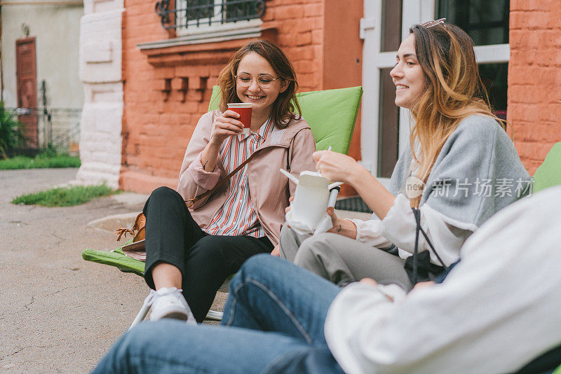 两个女人坐在院子里喝着咖啡吃着外卖