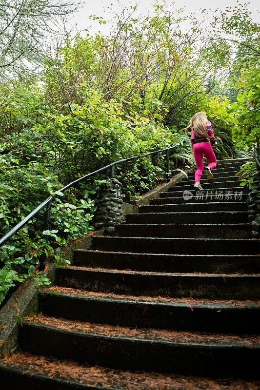 女人跑上潮湿的楼梯，周围环绕着野生的原生植物