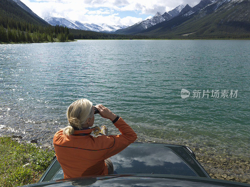 女人放松附近的山湖，在汽车引擎盖上