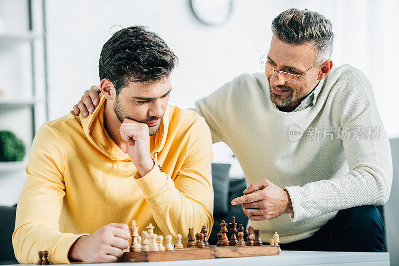 儿子和成熟的父亲周末一起在家下棋