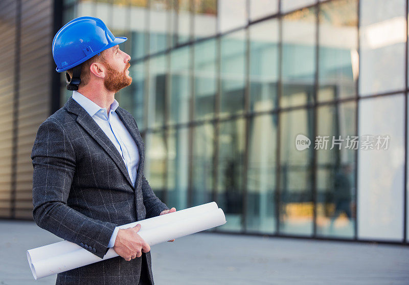 快乐的中年建筑师看着建筑工地。