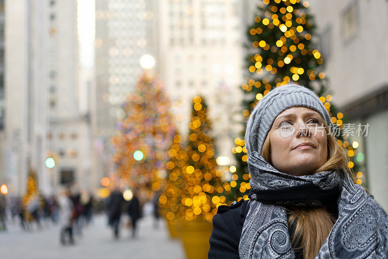 女性走在街道上的圣诞树在城市