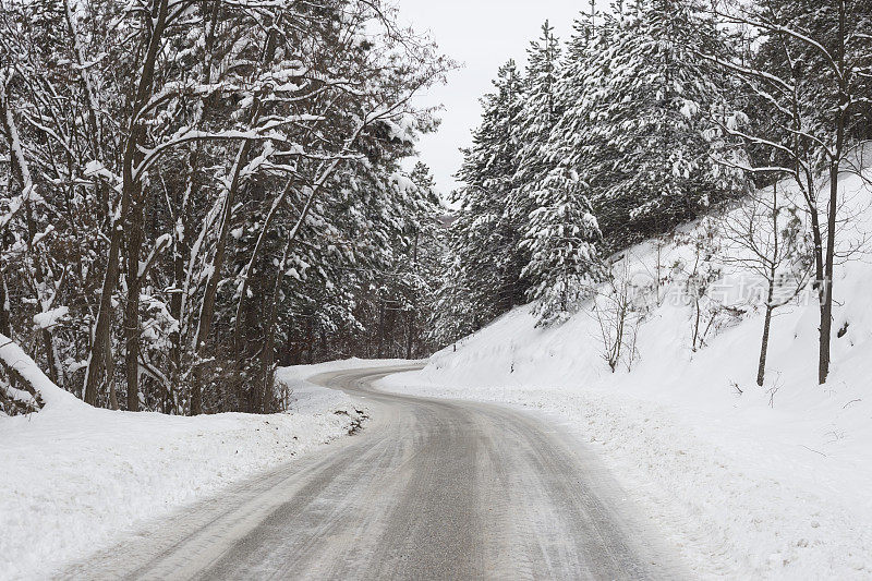 冰雪弯弯曲曲的道路穿过白雪覆盖的山林