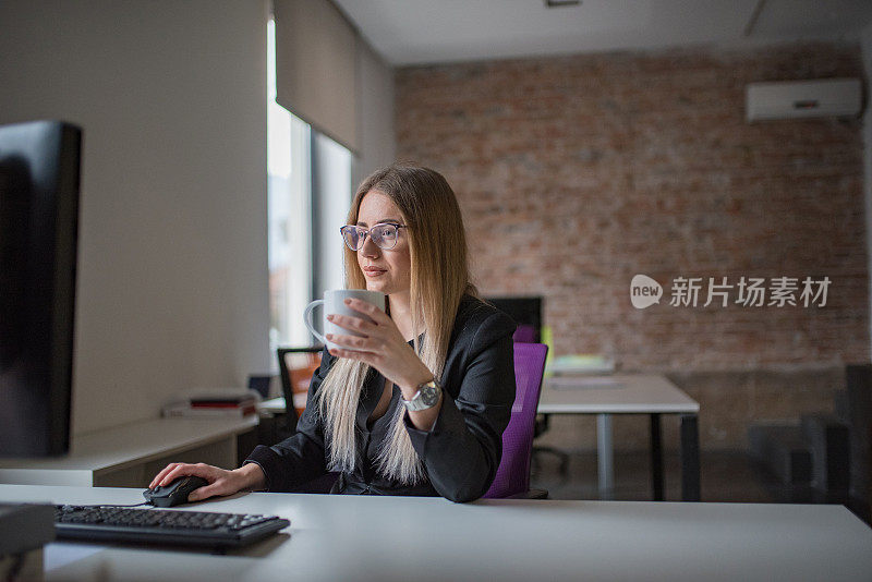 女商人用电脑，在办公桌前喝咖啡