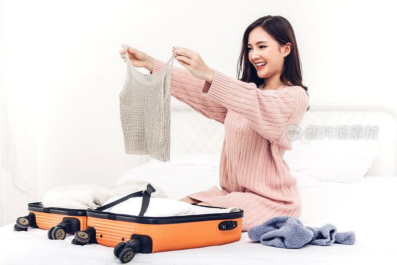 女人打包一个手提箱行李和背包在家里旅行。节日假期的概念