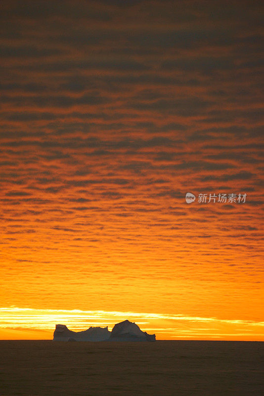 南极泻湖上的日落与漂流的冰山和雪峰的背景，勒梅尔海峡，南极洲