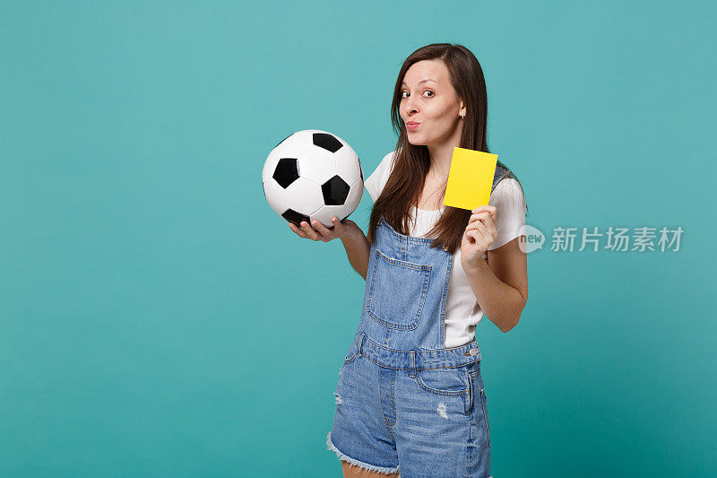 狡猾的女球迷用足球支持球队，黄牌建议球员从球场上退场孤立在蓝绿色的墙壁背景上。人情感，运动家庭休闲理念。