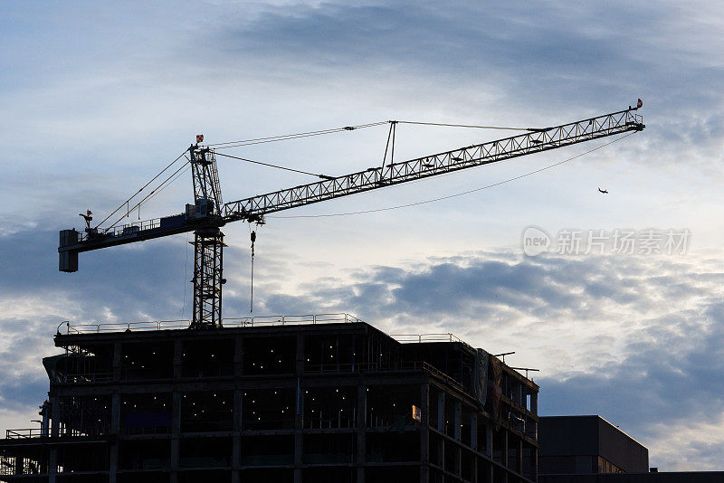 建筑顶部的施工起重机。下午轮廓