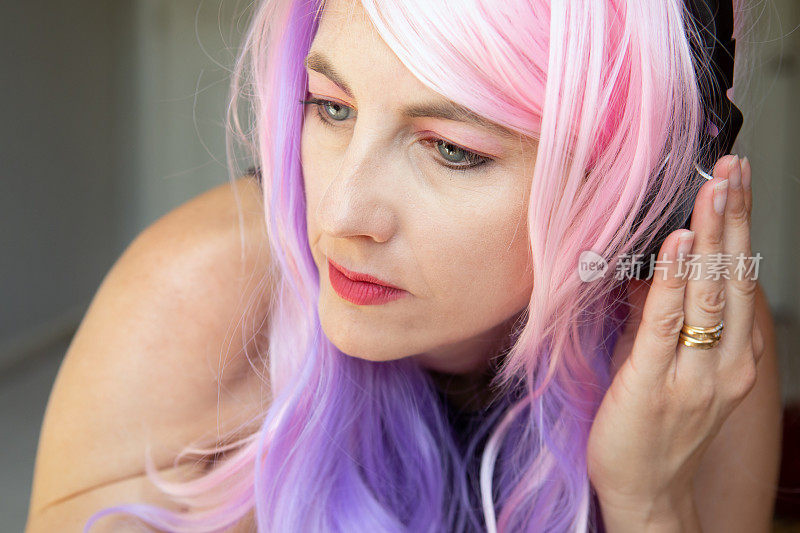 粉红和紫色头发的女人听音乐