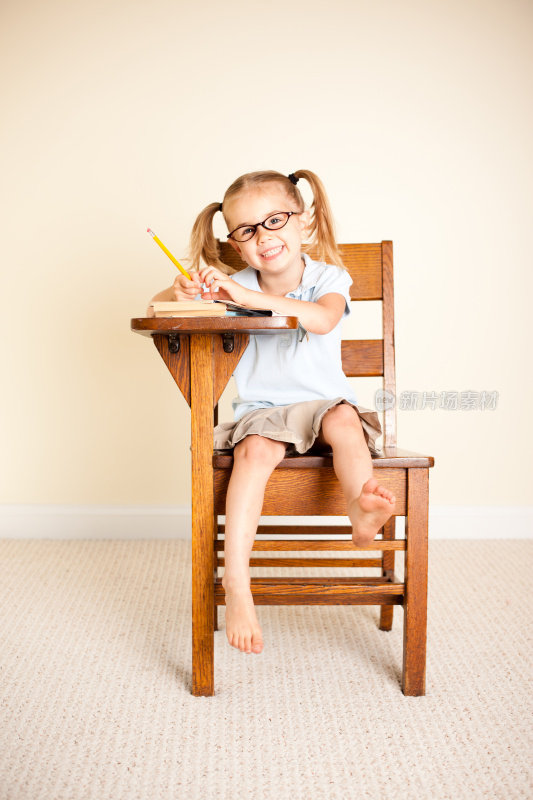 戴眼镜的快乐女学生坐在书桌前