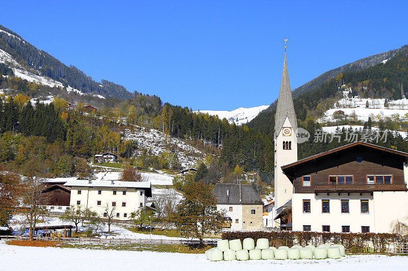 阿尔卑斯山的村庄，天主教哥特式教堂，瑞士小屋，雪，秋天的树林