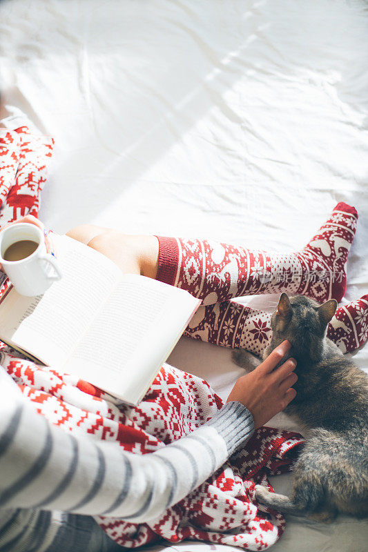 女孩和她的猫在床上看书