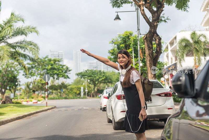 女人拿着手机，在市中心叫出租车