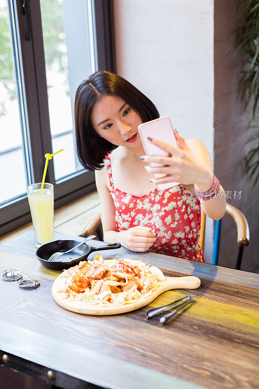 一名年轻的中国女子在餐厅用午餐自拍