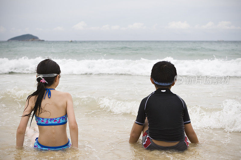 孩子们:小男孩和小女孩坐在海滩上