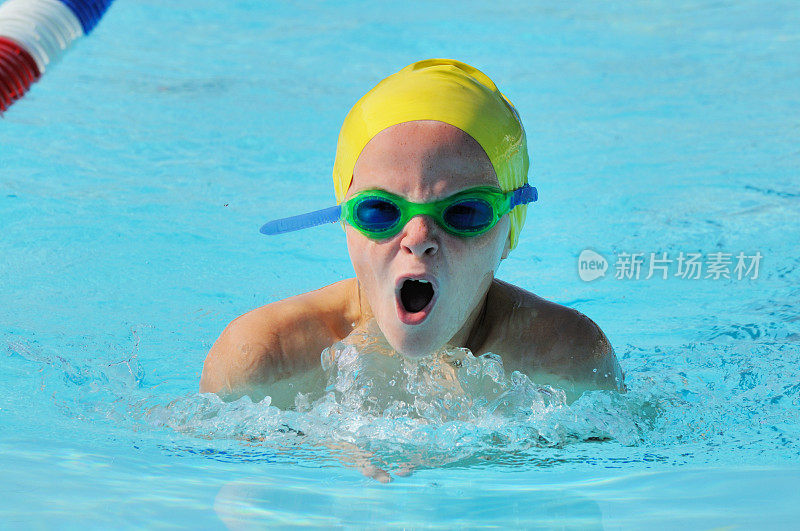 小男孩运动员在泳池比赛中游蛙泳