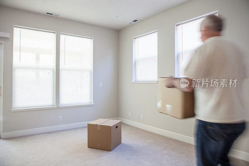 一个男人把箱子搬到一个空的白色房间里