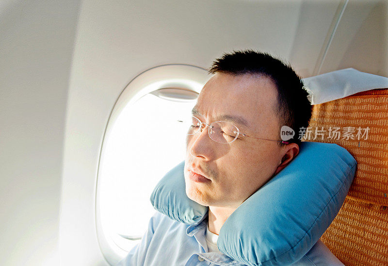 年轻的亚洲商人在飞机上睡觉