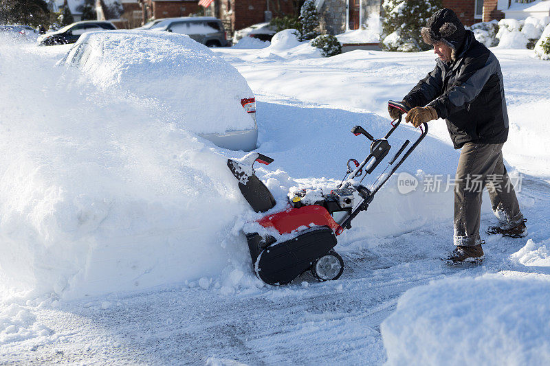 老人用吹雪机清理停在车里的雪