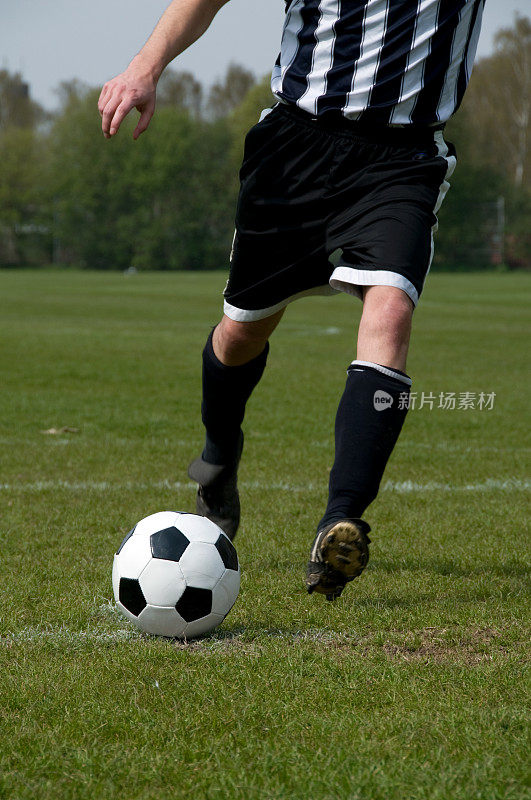 足球运动员跑向一个球并踢它
