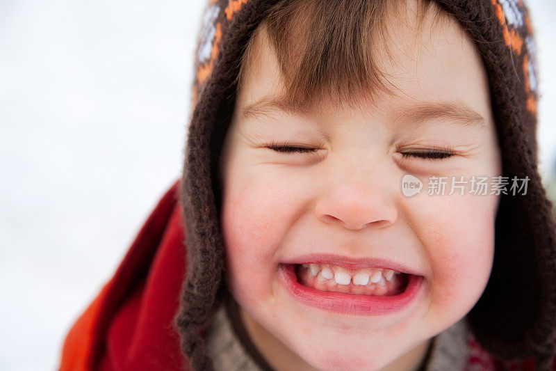 可爱的小男孩戴着温暖的帽子在外面的雪