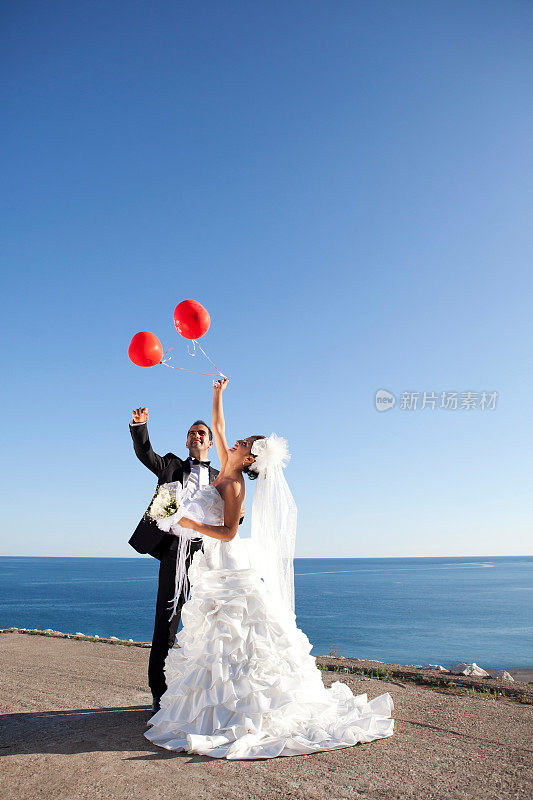 新婚夫妇在海边举着庆祝气球