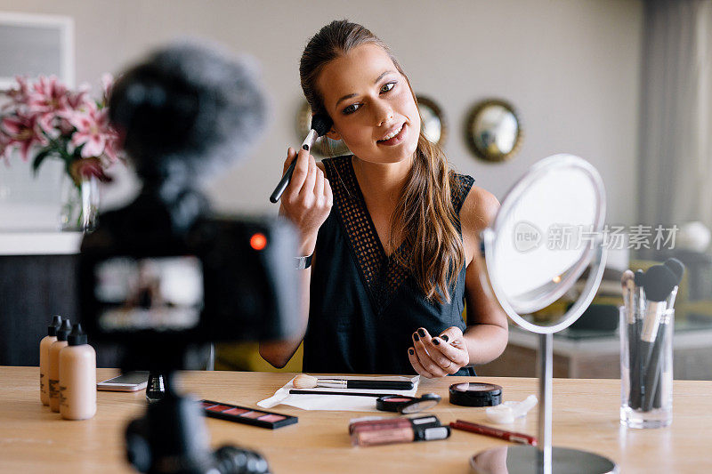 年轻的女视频博主正在录制一个化妆广播。