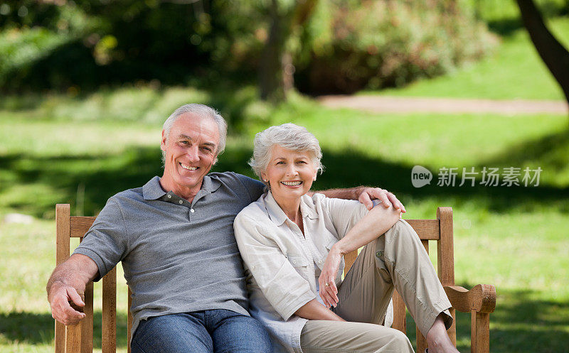 一对快乐的老年夫妇坐在公园的木凳上