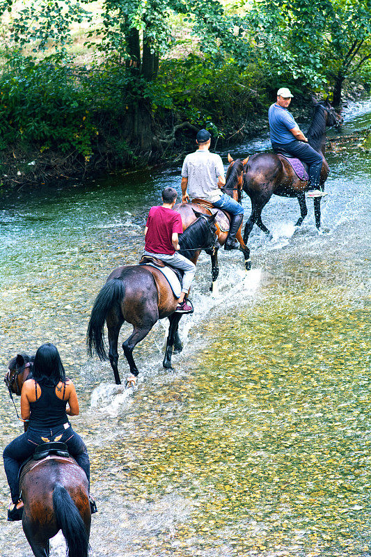 人们骑马疾驰过溪流