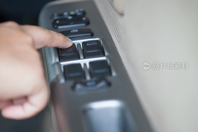 女人在车里用手按住控制车窗的按钮