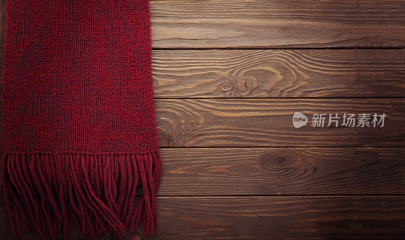 编织的紫红色围巾在一个深色的木制背景。