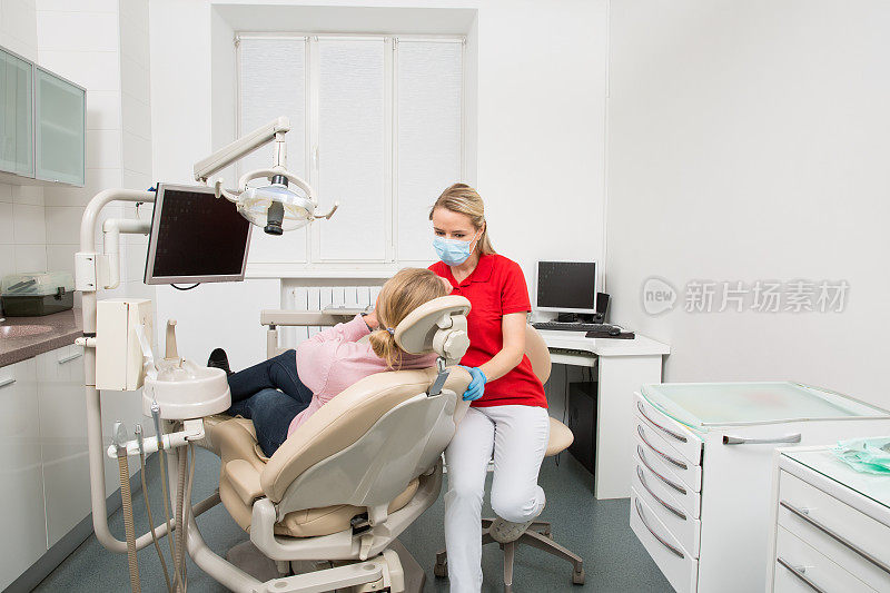 一个张开嘴的女人正在接受女牙医的牙齿检查。到牙科诊所进行牙齿检查。