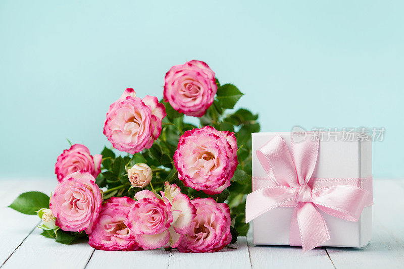 鲜花，玫瑰和礼品盒与丝带在古董桌上。生日、妇女或母亲节贺卡。