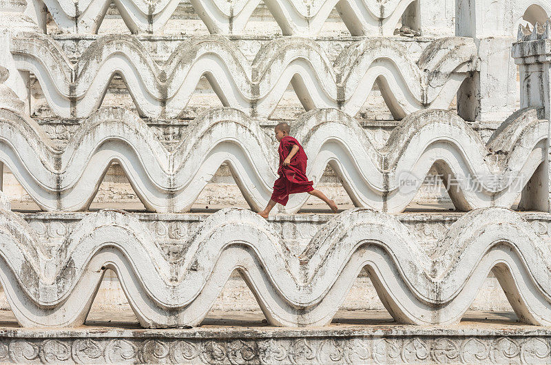 在缅甸曼德勒的蒲甘，年轻的和尚在米亚登丹塔上奔跑跳跃
