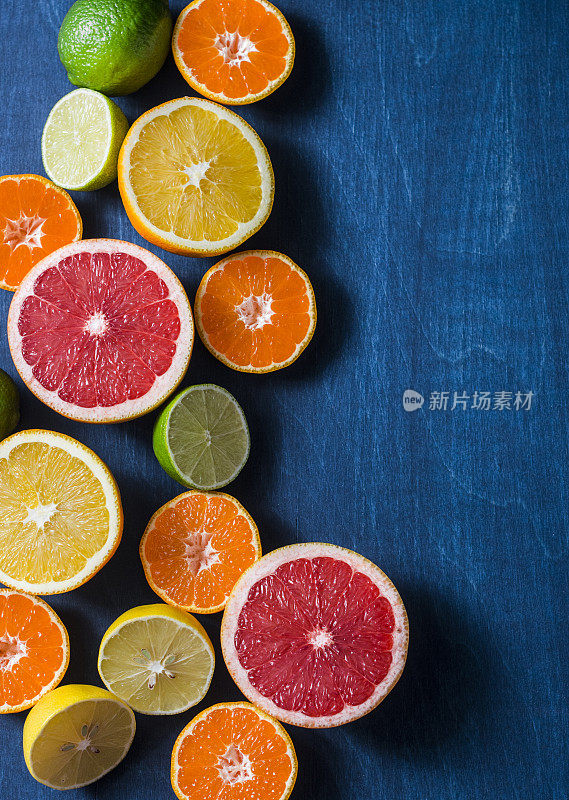 混合柑橘类水果在一个蓝色的背景，俯视图。橙子、葡萄柚、橘子、酸橙、柠檬——有机水果、素食健康食品理念。免费spac