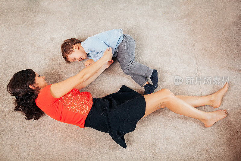 母亲和儿子在家里的地板上玩耍
