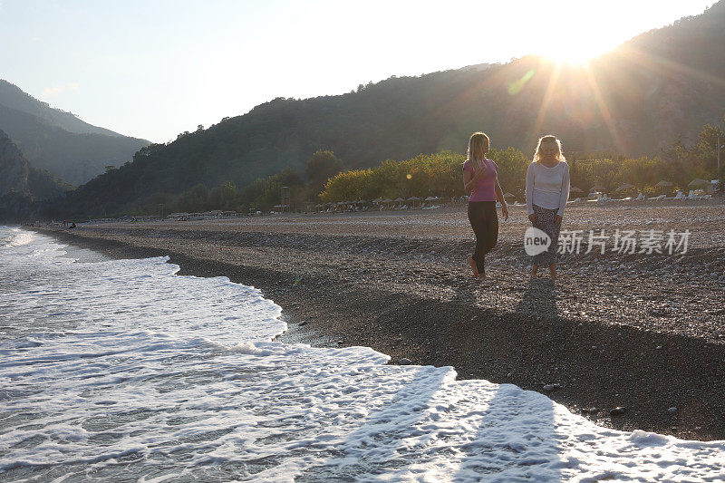 日出时，妇女们沿着海滩散步