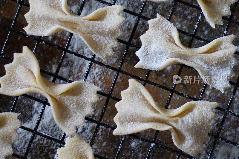 这是自制法法尔面食(蝴蝶结状或蝴蝶状)的特写，撒上面粉，放在金属丝冷却架上晾干，从高处俯瞰意大利美食