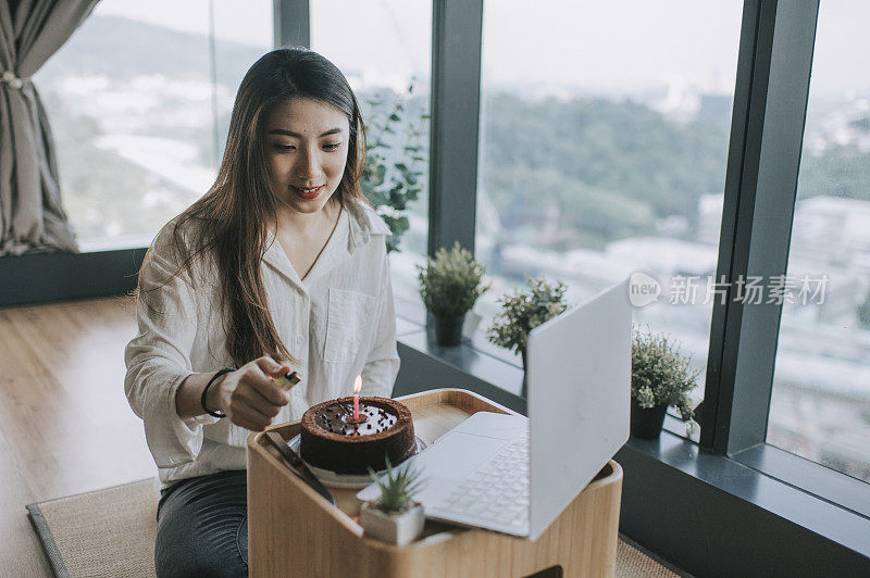 一位亚洲华裔年轻女性用笔记本电脑在线视频电话与朋友虚拟地庆祝自己的生日