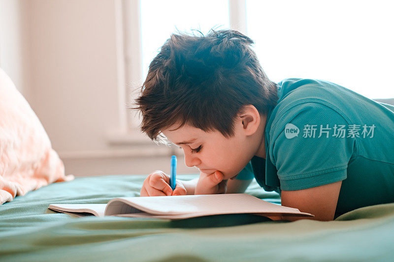 小男孩在床上做作业