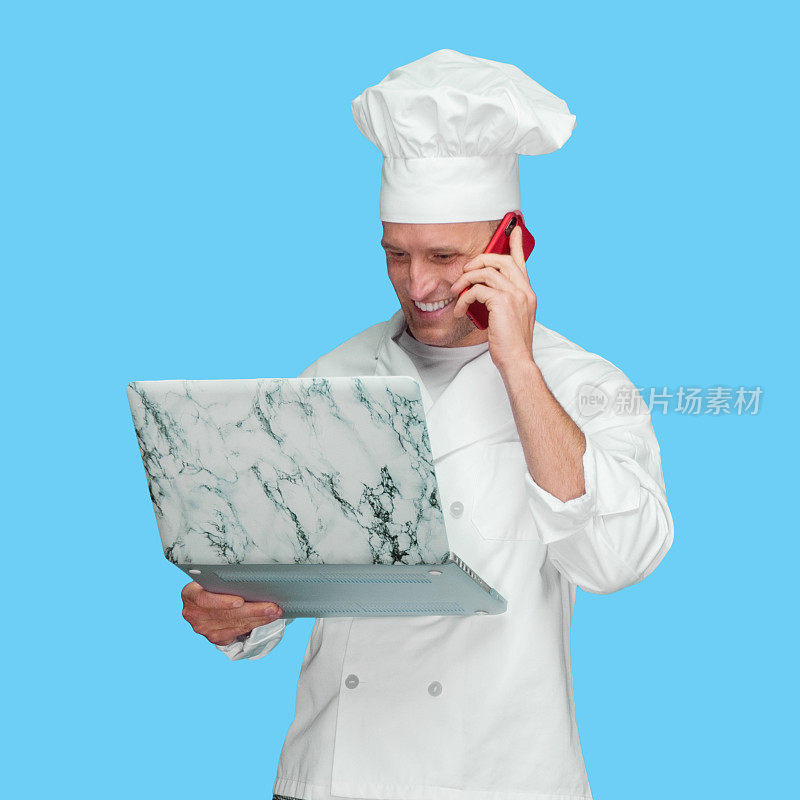 白人男厨师穿着制服站在蓝色背景前使用笔记本电脑